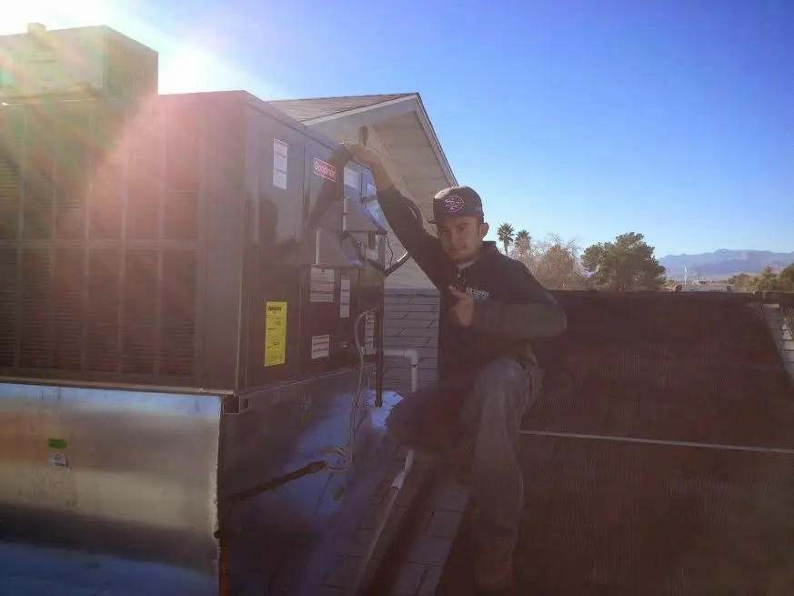 HVAC technician performing HVAC Inspection on a rooftop unit in Belmont